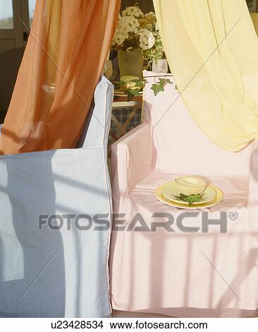 Close-up of orange and yellow voile drapes and director's chairs with pale blue and pink and loosecovers View Large Photo Image Picture - Close-up of orange and yellow voile drapes and director's chairs with pale blue and pink and loosecovers. Fotosearch