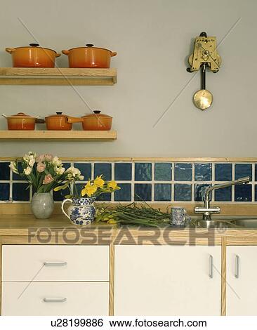 Close-up of orange 'Le Creuset' cooking pots above kitchen worktop with tiled splashback View Large Photo Image Stock Photograph - Close-up of orange 'Le Creuset' cooking pots above kitchen worktop with tiled splashback. Fotosearch
