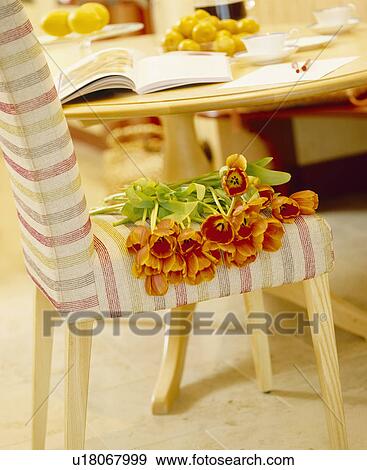 Close-up of orange tulips on striped upholstered chair View Large Photo Image Stock Photo - Close-up of orange tulips on striped upholstered chair. Fotosearch