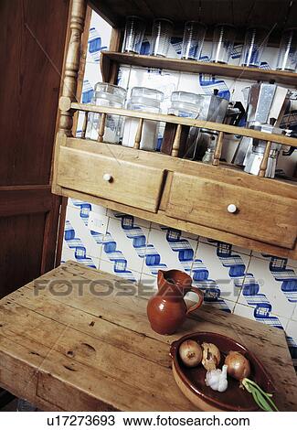 Stock Image - Close-up of pine shelves on blue+white tiled wall above pine cupboard. Fotosearch