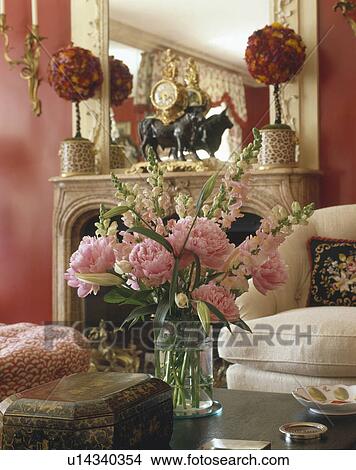 Close up of pink paeonies in glass vase on table in red trditional livingroom View Large Photo Image Picture - Close up of pink paeonies in glass vase on table in red trditional livingroom. Fotosearch