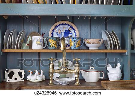 Close-up of plates and cups on shelf behind brass mixer taps View Large Photo Image Stock Photograph - Close-up of plates and cups on shelf behind brass mixer taps. Fotosearch