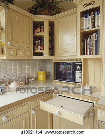 Close-up of pull-out shelf in small kitchen with pale wood units and microwave oven View Large Photo Image Picture - Close-up of pull-out shelf in small kitchen with pale wood units and microwave oven. Fotosearch