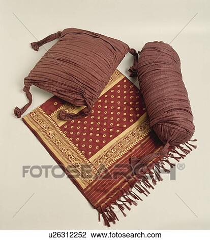 Stock Image - Close-up of ruched brown silk cushions on folded gold and rust-coloured Indian silk throw. Fotosearch