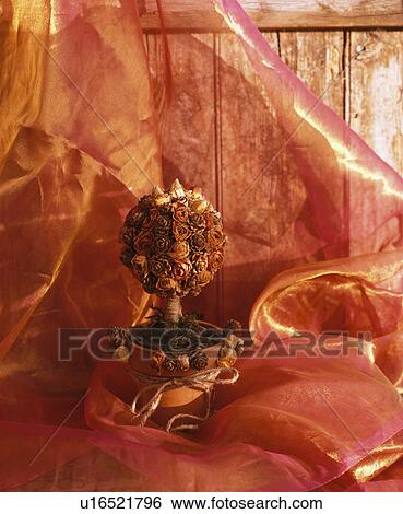 Stock Photograph - Close-up of small tree made from dried roses on metallic red organza. Fotosearch