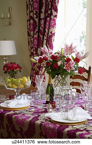 Stock Photograph - Close-up of table set for lunch with wine-glasses and glass vase of pink lilies on Designer's Guild cut-velvet cloth. Fotosearch