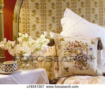Stock Photo - Close-up of tapestry cushion and pillows against upholstered bedhead. Fotosearch
