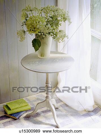 Close-up of vase of white wild-flowers on small circular stencilled table beside window with white voile curtain View Large Photo Image Stock Photo - Close-up of vase of white wild-flowers on small circular stencilled table beside window with white voile curtain. Fotosearch