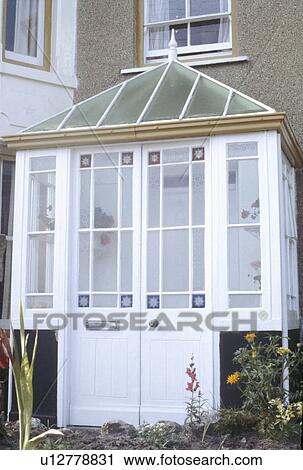 Stock Image - Close up of Victorian glass porch with half glazed stained glass doors. Fotosearch