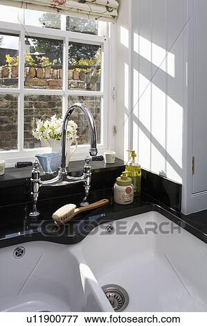 Stock Photo - Close-up of Villeroy + Boch double white sink and chrome tap below kitchen window. Fotosearch