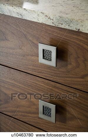 Stock Image - Close-up of walnut kitchen unit with pewter handles and granite worktop. Fotosearch