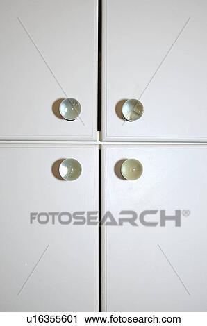 Stock Image - Close-up of white cupboard doors with glass handles. Fotosearch
