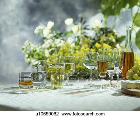 Stock Image - Close-up of wine glasses and bottle with flowers in the background. Fotosearch