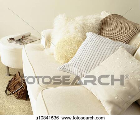 Stock Photograph - Close-up of woollen and faux fur cushions on cream sofa. Fotosearch