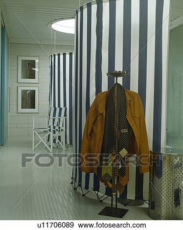 Stock Photo - Clothes on stand against blue striped canvas screen in hall with Pirelli flooring. Fotosearch