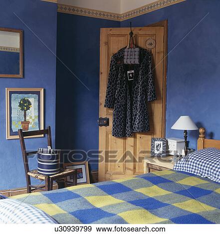 Stock Photo - Coat hanging on door in blue bedroom. Fotosearch