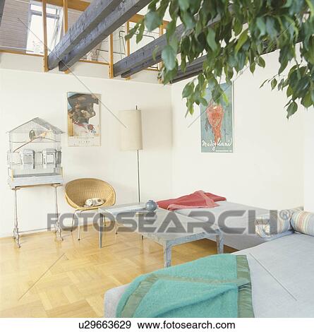 Colourful blankets on day-beds in loft conversion living room with wood-block flooring and black ceiling beams View Large Photo Image Stock Photo - Colourful blankets on day-beds in loft conversion living room with wood-block flooring and black ceiling beams. Fotosearch