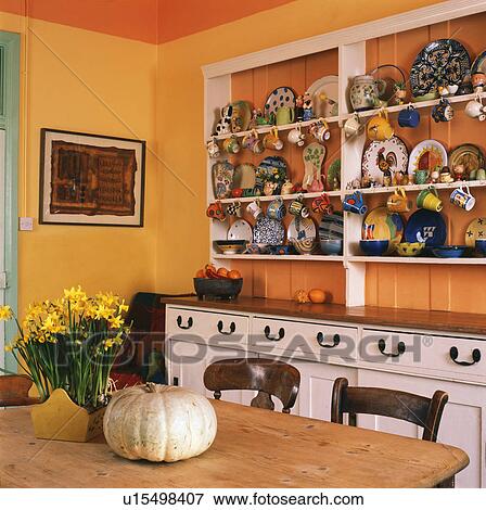 Colourful crockery on white shelves in orange dining room View Large Photo Image Stock Photo - Colourful crockery on white shelves in orange dining room. Fotosearch