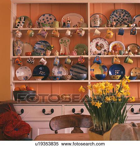 Colourful pottery on white fitted dresser in orange dining room View Large Photo Image Stock Photography - Colourful pottery on white fitted dresser in orange dining room. Fotosearch