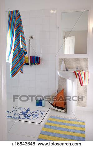 Colourful striped towel and model boat in modern white shower room with mirror above pedestal basin View Large Photo Image Stock Photo - Colourful striped towel and model boat in modern white shower room with mirror above pedestal basin. Fotosearch