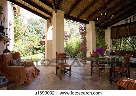 Comfortable armchair and dining table and chairs on veranda of Mallorcan house with view of garden View Large Photo Image Stock Image - Comfortable armchair and dining table and chairs on veranda of Mallorcan house with view of garden. Fotosearch