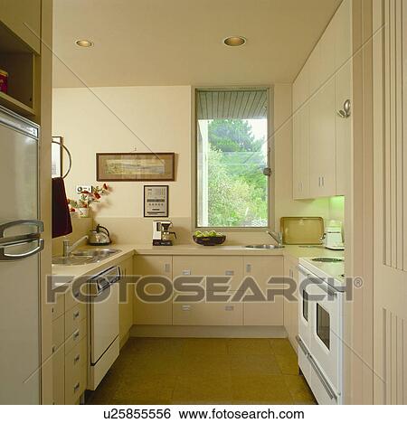 Stock Photograph - Compact modern kitchen with fitted cream melamine units. Fotosearch