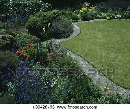 Stock Image - Country garden with paved path between summer border and newly-mown lawn. Fotosearch