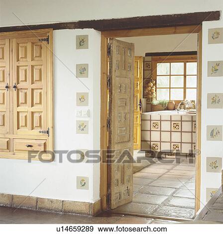 Stock Photo - Country hall with door open door to simple kitchen with stone flooring. Fotosearch