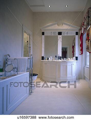 Stock Photo - Cream carpet in bathroom with double mirrors above basins in fitted vanity unit. Fotosearch