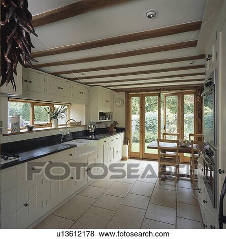 Cream ceramic floor tiles in country kitchen with cream fitted units View Large Photo Image Stock Photo - Cream ceramic floor tiles in country kitchen with cream fitted units. Fotosearch