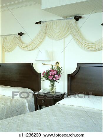 Cream Drapes On Poles Above Twin Beds In White Bedroom With White