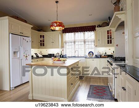 Cream fitted cupboards and units in country kitchen with island unit View Large Photo Image Stock Image - Cream fitted cupboards and units in country kitchen with island unit. Fotosearch