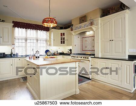 Cream fitted cupboards and units in country kitchen with island unit View Large Photo Image Stock Image - Cream fitted cupboards and units in country kitchen with island unit. Fotosearch