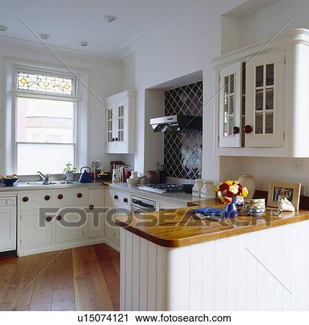 Cream fitted traditional kitchen with polished wooden worktop on cream painted peninsular unit View Large Photo Image Stock Image - Cream fitted traditional kitchen with polished wooden worktop on cream painted peninsular unit. Fotosearch