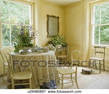 Cream painted antique chairs at circular table with cream cloth in elegant cream dining room with wooden flooring View Large Photo Image Stock Photo - Cream painted antique chairs at circular table with cream cloth in elegant cream dining room with wooden flooring. Fotosearch