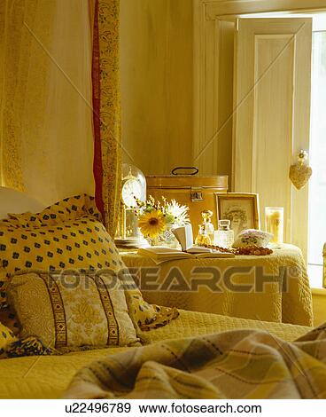 Stock Photo - Cream quilted cloth on bedside table beside bed with patterned cushions. Fotosearch