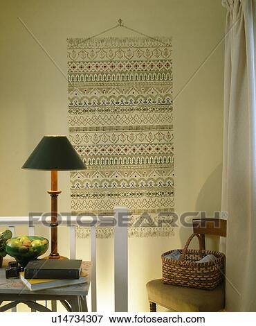 Cross-stitch wall-hanging on landing with lighted lamp on small table View Large Photo Image Stock Photo - Cross-stitch wall-hanging on landing with lighted lamp on small table. Fotosearch