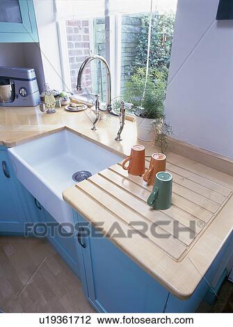 Cups on draining board beside white ceramic sink in turquoise kitchen View Large Photo Image Stock Image - Cups on draining board beside white ceramic sink in turquoise kitchen. Fotosearch