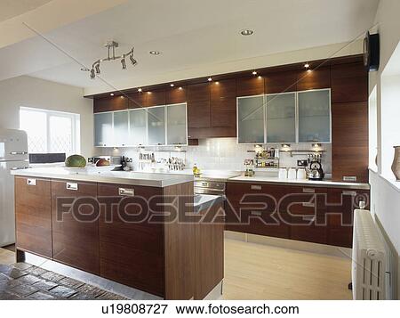 Dark brown fitted units in modern kitchen with track lighting View Large Photo Image Stock Photo - Dark brown fitted units in modern kitchen with track lighting. Fotosearch
