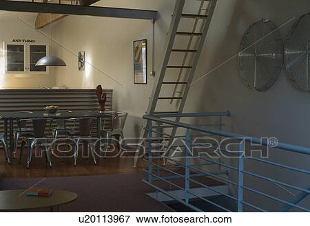 Dining area with metal chairs and glass table in loft conversion View Large Photo Image Stock Photo - Dining area with metal chairs and glass table in loft conversion. Fotosearch