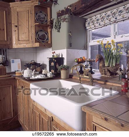 Double white ceramic sink below window in fitted pine cottage kitchen View Large Photo Image Stock Photography - Double white ceramic sink below window in fitted pine cottage kitchen. Fotosearch
