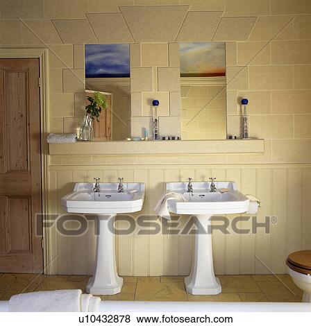 Stock Photo - Double white pedestal basins below mirrors in townhouse bathroom. Fotosearch
