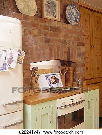 Exposed brick wall above oven and hob in green fitted unit with wooden worktop View Large Photo Image Stock Photo - Exposed brick wall above oven and hob in green fitted unit with wooden worktop. Fotosearch