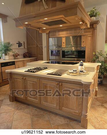 Extractor in fitted wooden unit above hob in island unit in large country kitchen View Large Photo Image Stock Image - Extractor in fitted wooden unit above hob in island unit in large country kitchen. Fotosearch