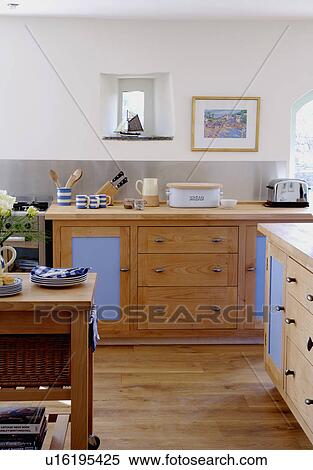 Fitted wooden units and wooden flooring in white coastal kitchen with stainless-steel splashbacks View Large Photo Image Stock Photography - Fitted wooden units and wooden flooring in white coastal kitchen with stainless-steel splashbacks. Fotosearch