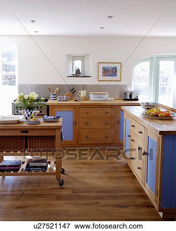Fitted wooden units wuth blue doors in white coastal kitchen with wooden flooring View Large Photo Image Stock Photo - Fitted wooden units wuth blue doors in white coastal kitchen with wooden flooring. Fotosearch