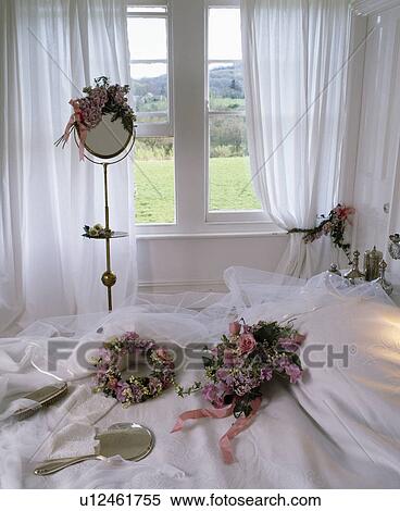 Stock Photography - Floral wedding head-dresses and veil on white bed in country bedroom. Fotosearch