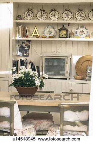 Stock Photography - Flowering plant on table in small cream dining room. Fotosearch
