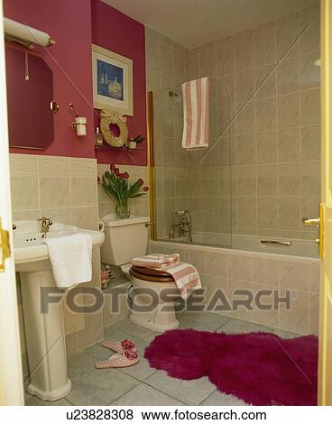 Stock Photo - Fluffy pink bathmat on floor on pink bagthroom with creaam wall tiles. Fotosearch