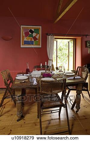 Stock Photo - Folding bamboo chairs at table in red living room with wooden flooring. Fotosearch